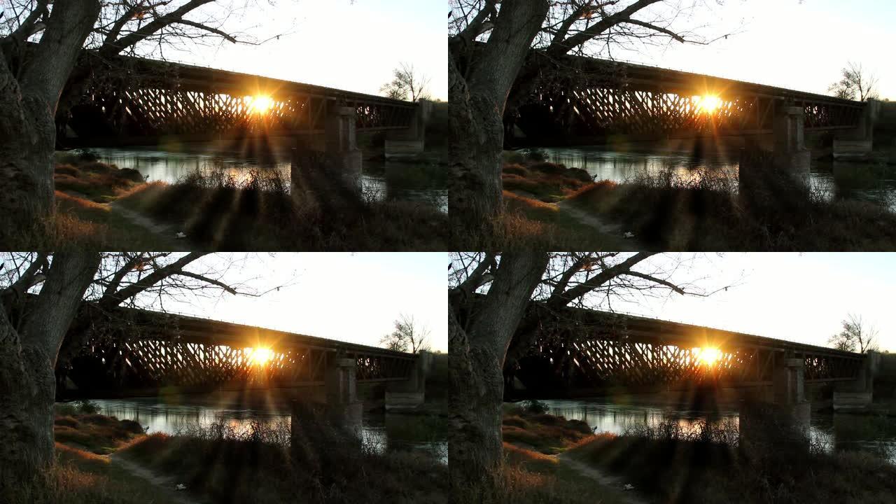 日落时废弃的火车桥在河上。