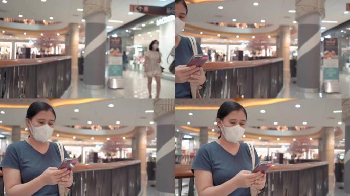在新型冠状病毒肺炎冠状病毒大流行期间，在超市购物中心使用智能手机使用n95口罩的女性
