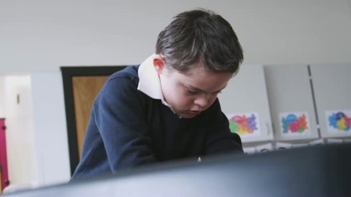 患有唐氏综合症的小学生站在教室的桌子上玩耍，低角度