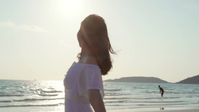 慢动作 -- 年轻的亚洲女人在海滩上散步。晚上日落时，美丽的女性快乐放松在海边的海滩上散步。生活方式