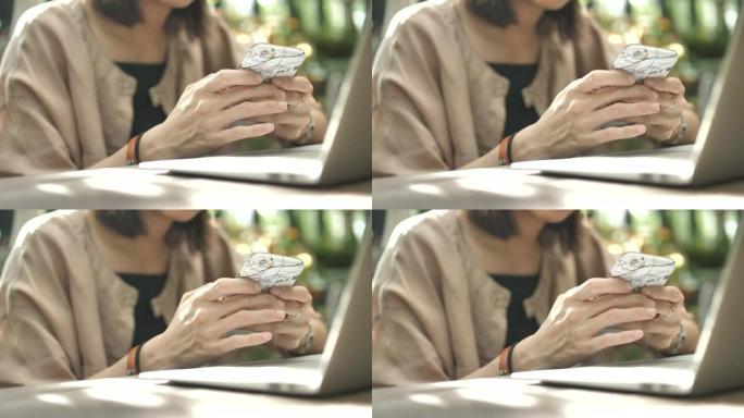 在咖啡馆使用带笔记本电脑的智能手机的女人的手的特写