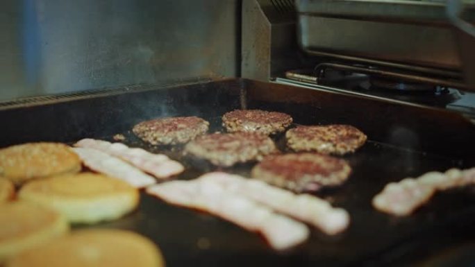 在烤架上准备的肉饼的美味特写镜头。新鲜的碎牛肉在热电烤架上烤。库克正在把肉末变成汉堡的肉饼，并用盐调