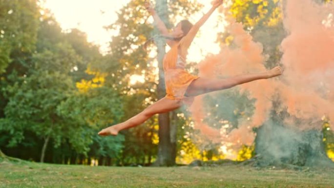 MS超级慢动作优雅的年轻女子在公园里用橙色烟雾弹跳跃分裂