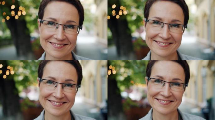 戴着眼镜的成熟女商人在户外相机微笑的特写肖像