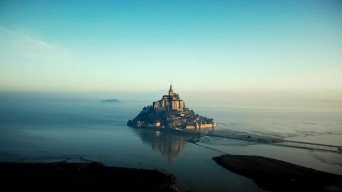 无人机飞向史诗般的日出圣米歇尔山，诺曼底被雾海包围的著名岛屿堡垒城堡。