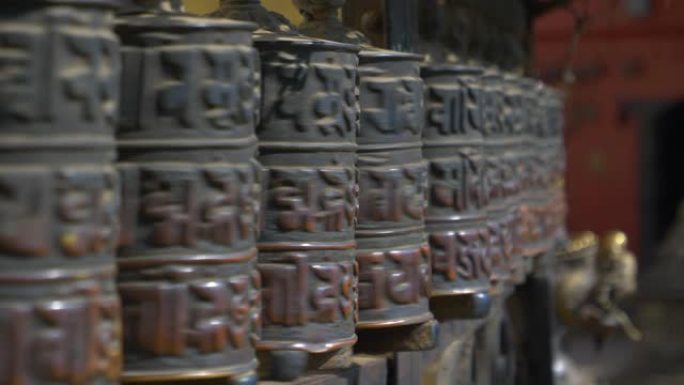 特写: 在印度教寺庙内旋转的金属祈祷轮的电影镜头。