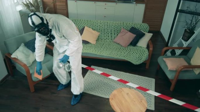 家具的消毒是由一个穿着防护服的人完成的。新型冠状病毒肺炎大流行期间的消毒过程。