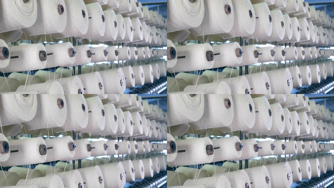带有白线的线轴正在缓慢旋转。现代纺织厂。
