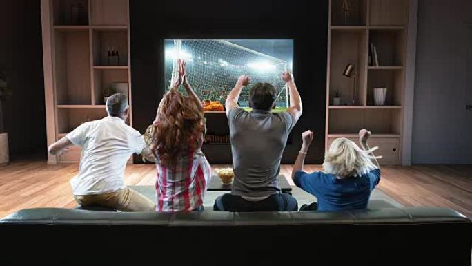 一群学生正在电视上观看足球时刻并庆祝进球