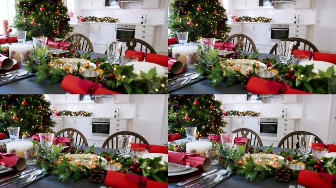装饰精美的圣诞餐桌，餐厅的盘子上摆放着圣诞饼干，背景是圣诞树和厨房