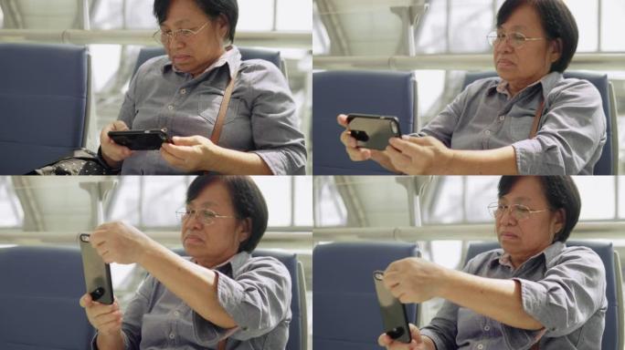 亚洲高级女性乘客在航站楼机场使用智能手机等待她的航班