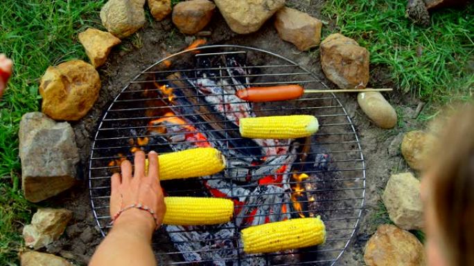 朋友在篝火上烤热狗和玉米的高角度视图4k