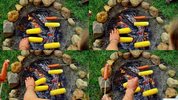 朋友在篝火上烤热狗和玉米的高角度视图4k