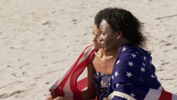 包裹着美国国旗的夫妇一起坐在海滩上4k