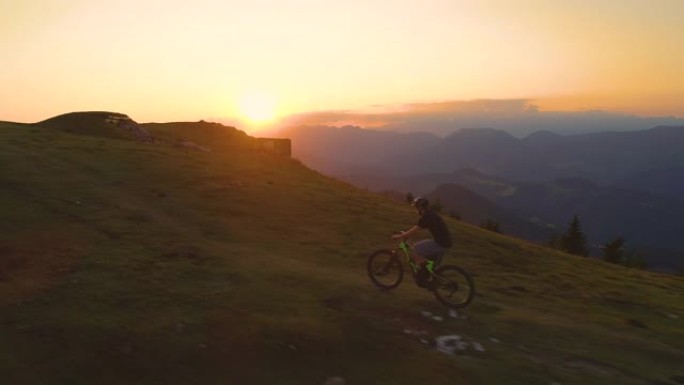 无人机: 金色的日落照亮了山地自行车手上坡的道路。