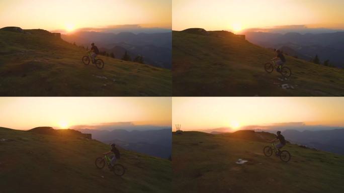无人机: 金色的日落照亮了山地自行车手上坡的道路。