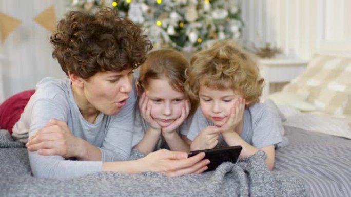 妈妈和孩子们在智能手机上观看圣诞节卡通