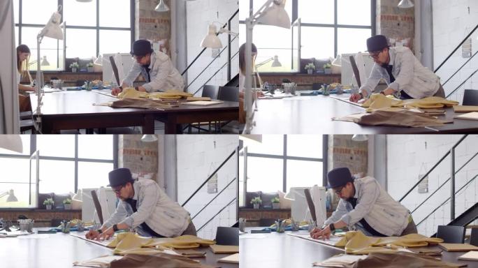 男裁缝用粉笔在工作室的织物上绘画