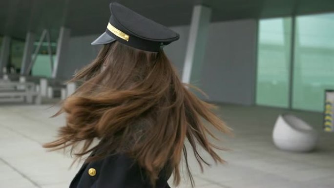 欢快的女人在机场背景前穿着飞行员服装跳舞