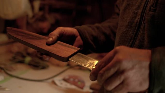 特写: Bladesmith将完成的传统刀插入木制护套。