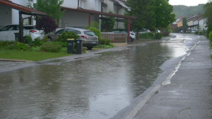 慢动作: 雨水覆盖了经过郊区梯田房屋的道路