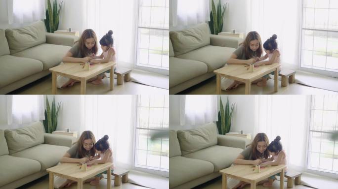 快乐的亚洲女孩和妈妈在家里的客厅用蜡笔画画。