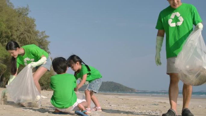 一群穿着绿色t恤的志愿者用装满垃圾的塑料袋清理海滩。慢动作。安全生态概念。4k分辨率。