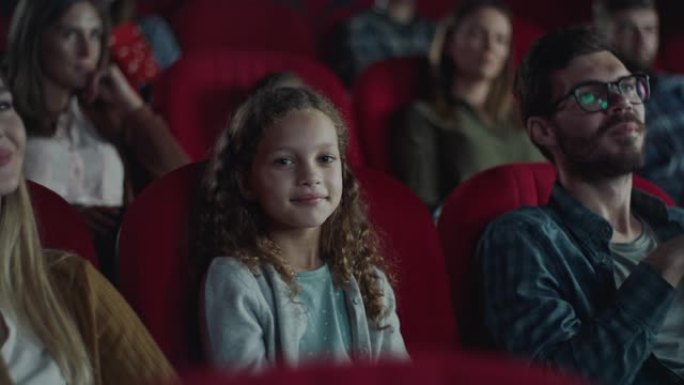 电影院里的小女孩看电影观众金发女孩