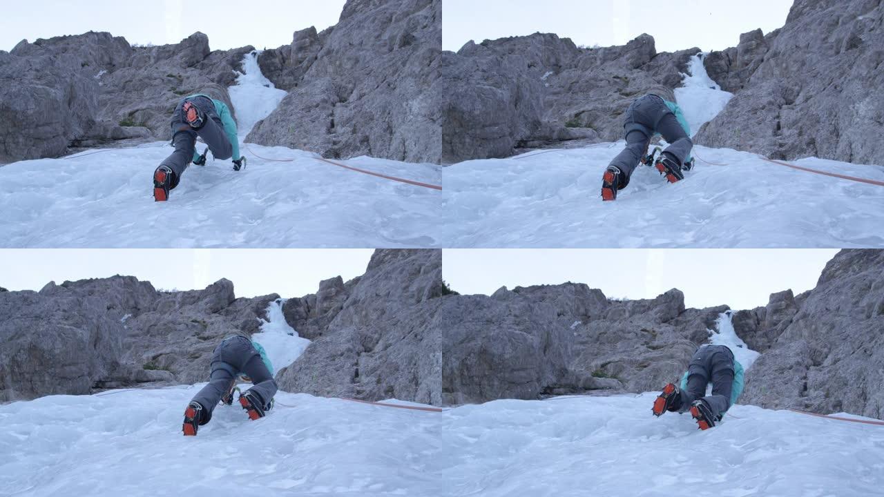 慢动作，自下而上: 女攀冰者将冰爪踢进坚硬的冰中。