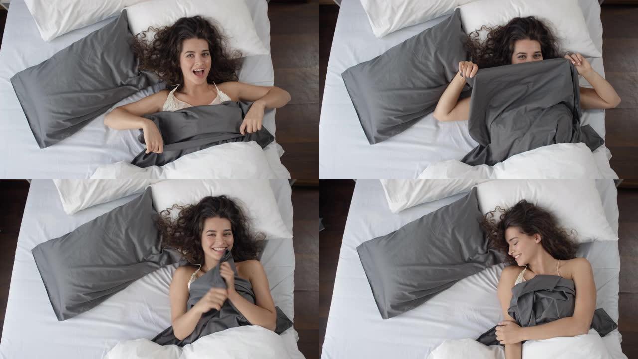 年轻顽皮的女人在床上微笑着为相机摆姿势