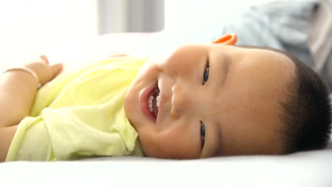 男婴看着相机微笑，躺在床上