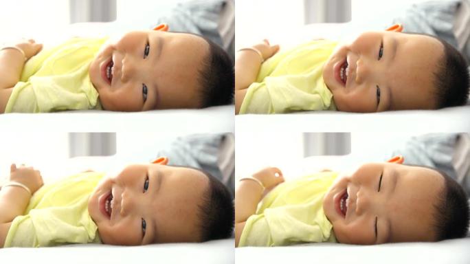 男婴看着相机微笑，躺在床上