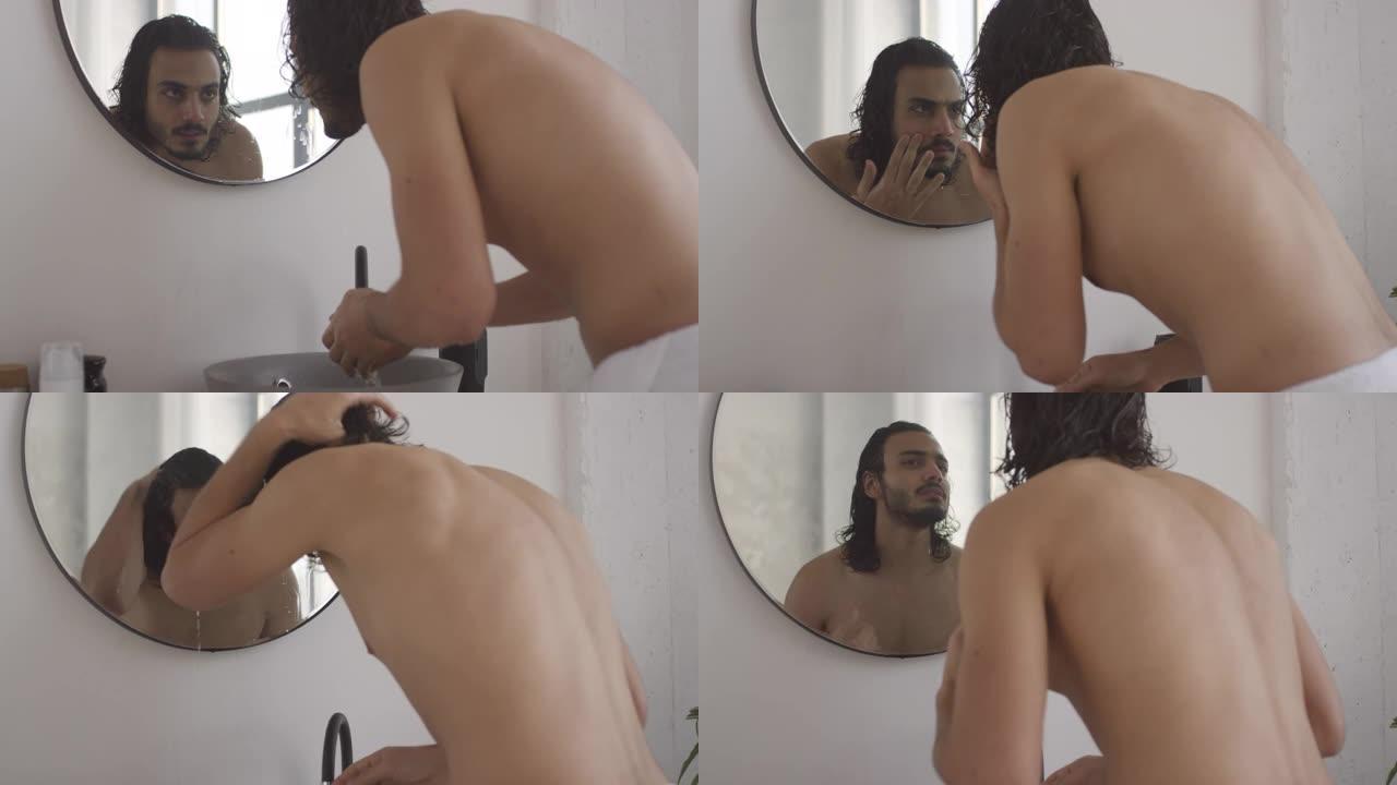 年轻的阿拉伯男子在浴室洗脸和照镜子
