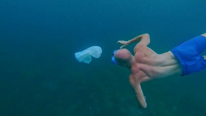 清洁海洋。男子在海面下抓塑料袋