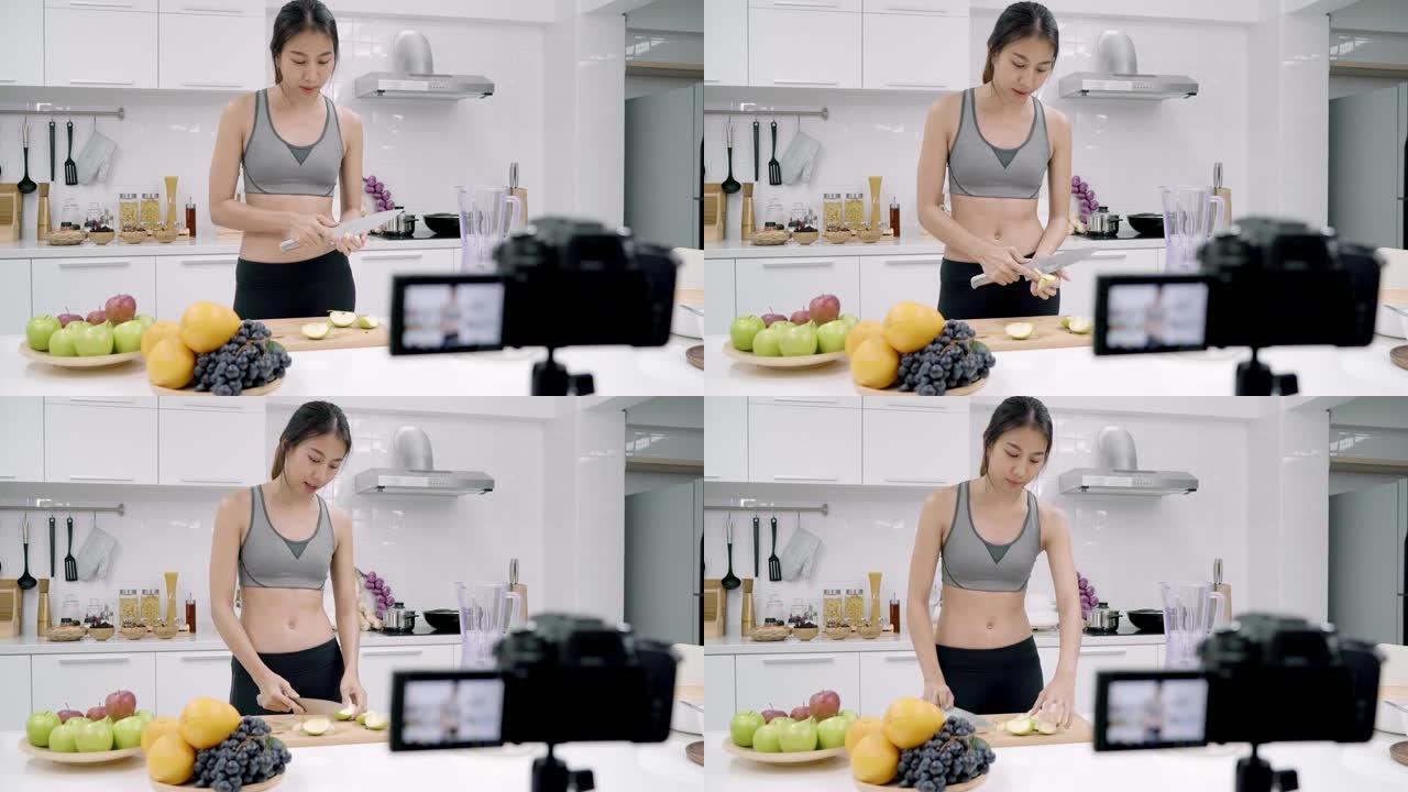 博主运动的亚洲女性使用相机录制如何为订户制作苹果汁视频，女性使用有机水果自己在家制作苹果汁。健康食品