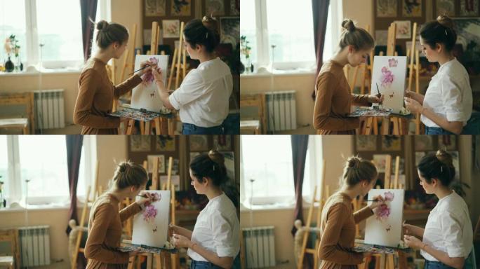 艺术学校的女学生正在用油画绘画花朵，而她的老师长得漂亮的年轻女子则在给她的建议中指向图片。