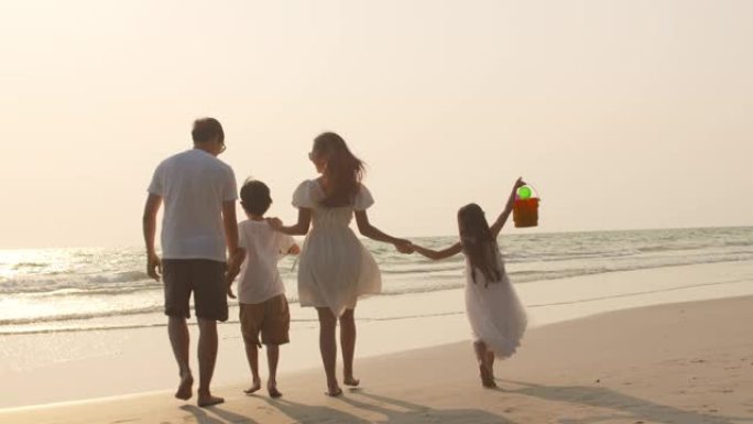 爸爸，妈妈和孩子在日落时放松在海边散步。4k慢动作。