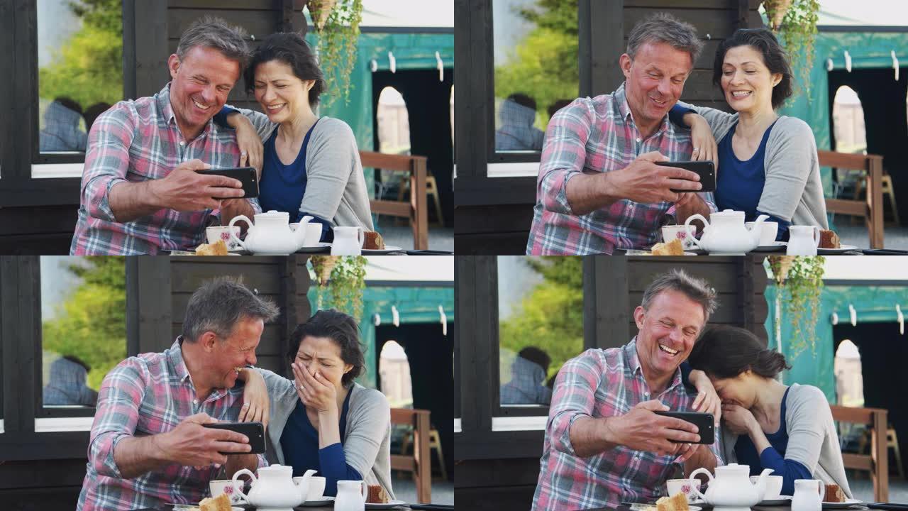 花园中心咖啡馆的成熟夫妇在手机上自拍