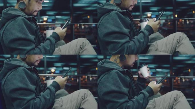 商人坐在机场，晚上使用手机。