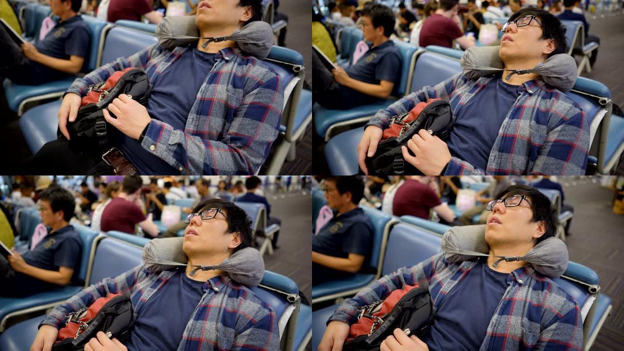 亚洲旅客男子与旅行颈枕睡在机场候机楼