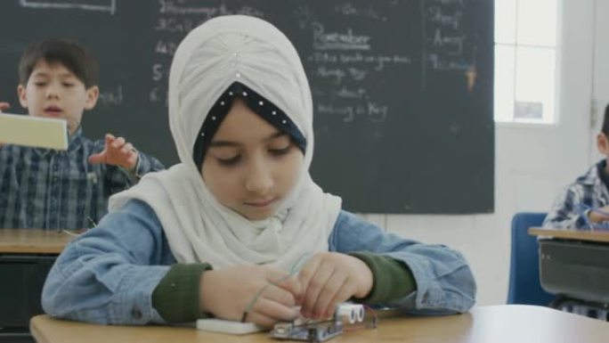 在学校办公桌前工作的年轻穆斯林女孩