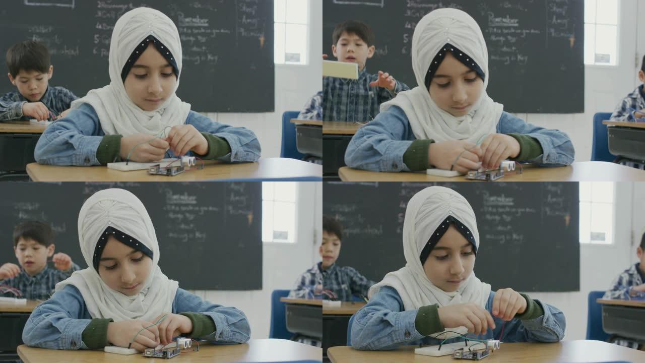 在学校办公桌前工作的年轻穆斯林女孩