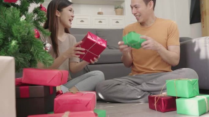 亚洲夫妇包装和包装圣诞礼物在圣诞节期间装饰他们家里的客厅。生活方式男女快乐庆祝夏季圣诞节和新年概念。