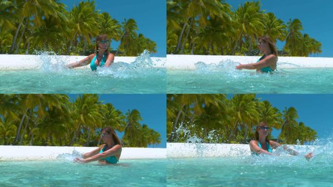 慢动作: 快乐的旅游女孩用手溅起碧绿的海水