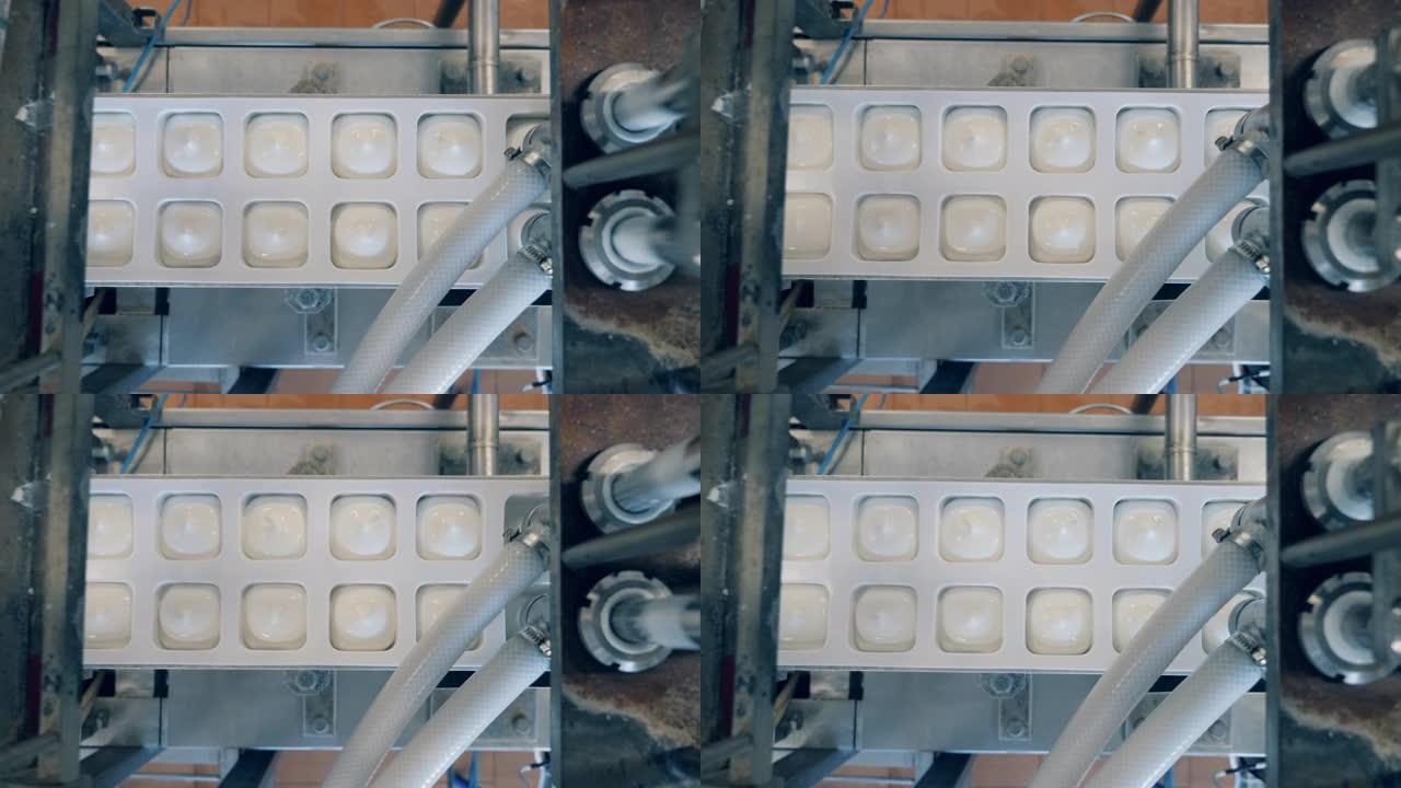 现代设备将酸奶倒入容器中。生产和包装食品和饮料的自动化设备。