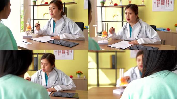 物理治疗师向患者展示脊柱模型上的问题区域，并解释她疼痛的原因。