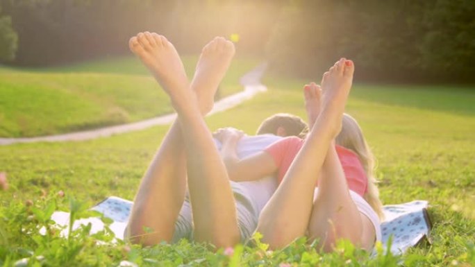 特写无法辨认的赤脚夫妇躺在草地中间的毯子上