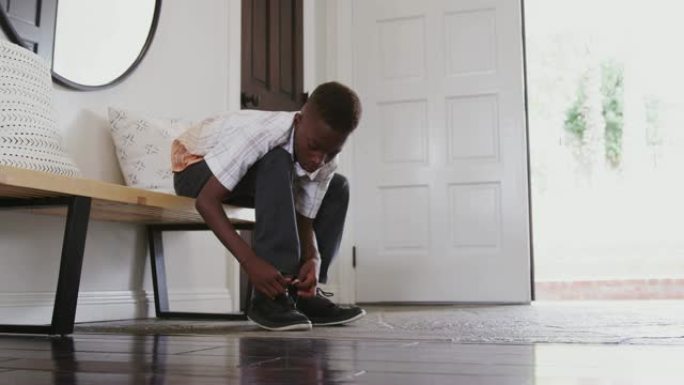 低角度视角青少年前黑人男孩离家前系鞋带，特写