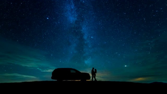 这对夫妇站在星空背景上的一辆汽车附近。时间流逝
