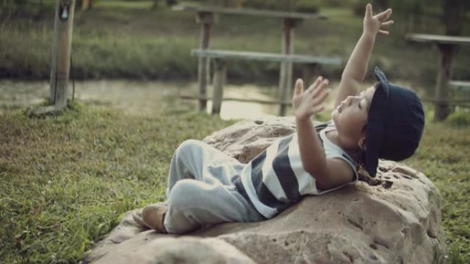 亚洲男婴在公园的岩石上玩耍和享受。